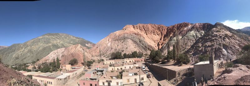 Panoramic view of buildings and mountains against blue sky