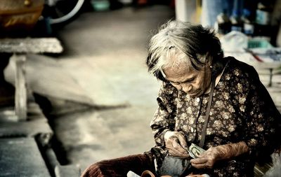 Woman holding paper currency while sitting on chair