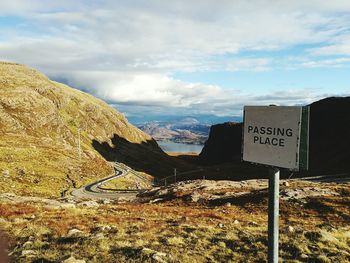 Road sign on landscape against sky