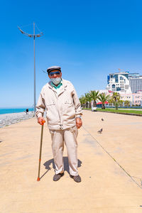 Full length portrait of young man standing against sky