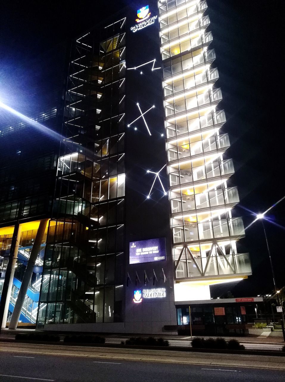 LOW ANGLE VIEW OF ILLUMINATED MODERN BUILDINGS AT NIGHT