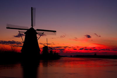 Silhouette cranes against romantic sky at sunset