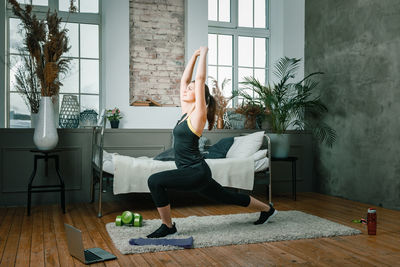 A young woman goes in for sports at home, online workout from the laptop. 