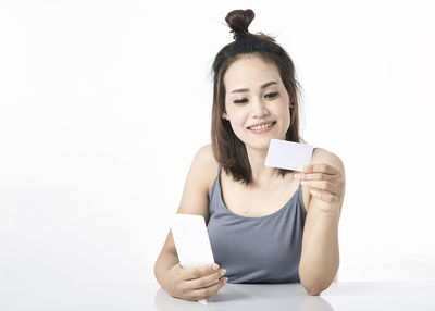 Portrait of smiling young woman using phone against white background