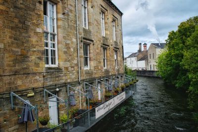 Buildings by canal against sky