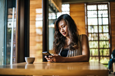 Young woman using mobile phone in cafe