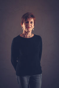 Portrait of a smiling young woman against wall