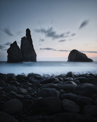 Rocks on beach against sky during sunset