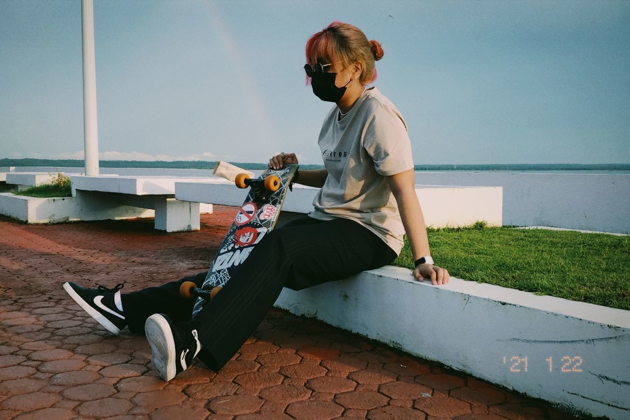 SIDE VIEW OF WOMAN SITTING ON WALL