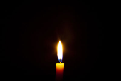 Close-up of lit candle against black background