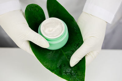 Close-up of hand face cream bottle in leaf