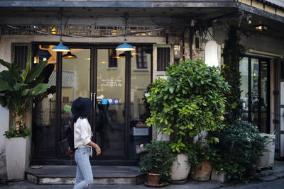 Side view of woman walking by cafe on street