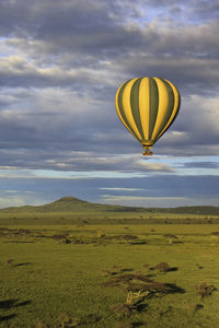 Hot air balloons flying over landscape against sky during sunset