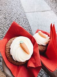 High angle view of ice carrot cupcakes on hands