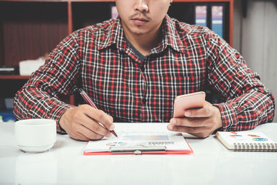 Midsection of man reading book while sitting on table