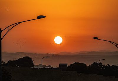 Silhouette street light against orange sky during sunset