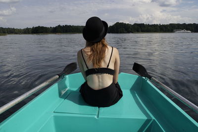 Rear view of woman sitting on boat in lake