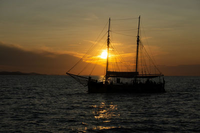 Sailboat sailing on sea against sky during sunset