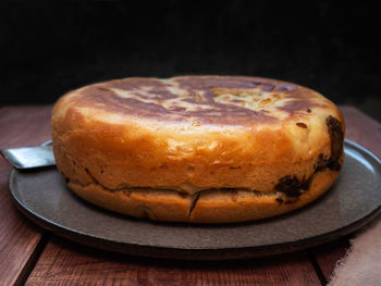 Large closed homemade cake shot from the side on a gray ceramic plate at close range