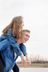 Side view of a smiling young woman against sky