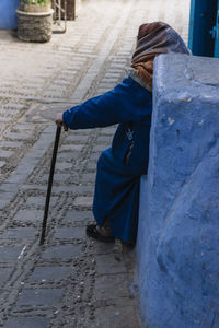 Rear view of woman sitting on footpath