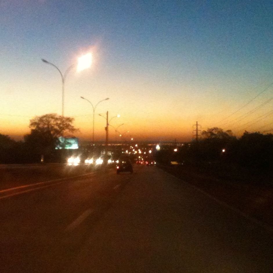 transportation, sunset, road, street light, car, the way forward, silhouette, electricity pylon, sky, street, mode of transport, land vehicle, sun, clear sky, illuminated, diminishing perspective, road marking, dusk, orange color, copy space