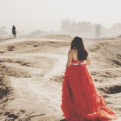 Rear view of woman walking on sand at beach