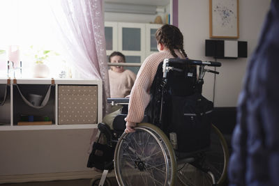 Teenage disabled girl on wheelchair in front of mirror