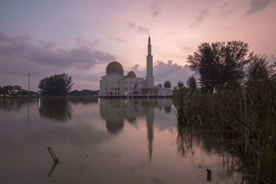 Reflection of church in lake against sky during sunset