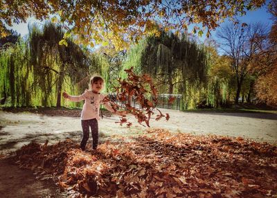 Full length of boy standing by tree during autumn