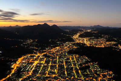 Aerial view of illuminated cityscape against sky at sunset