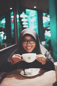 Portrait of smiling man holding coffee cup in restaurant