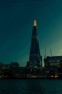 Low angle view of illuminated shard london bridge by river against sky at night