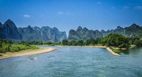 Scenic view of river by mountains against clear sky