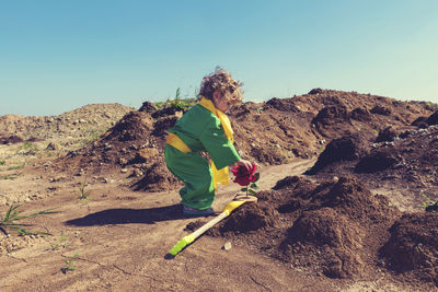 Side view of boy on land against sky