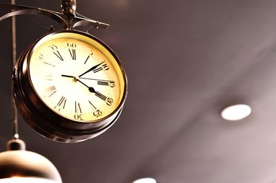 Low angle view of clock hanging against ceiling