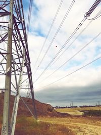 Low angle view of electricity pylon on field against sky