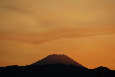 Scenic view of silhouette mountain against orange sky