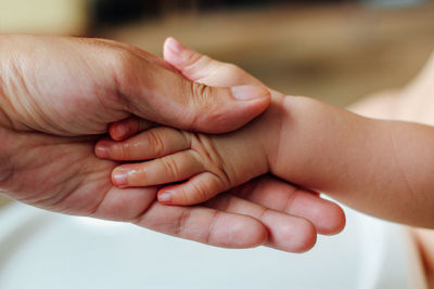 Cropped image of hands holding baby hand