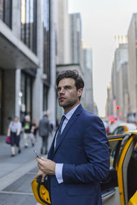 Businessman exiting yellow taxi in manhattan