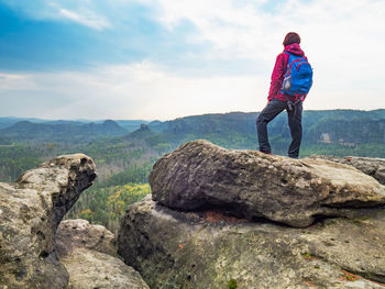 Rear view of man standing on rock against sky