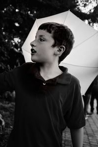 Boy looking away while standing against trees