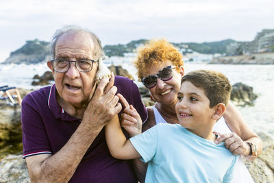 Grandparents and grandson playing with a shell on the beach