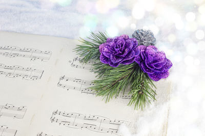 High angle view of sheet music with artificial purple flowers