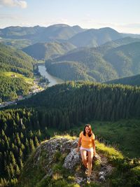 High angle view of woman sitting on rock against landscape