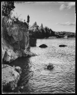 Rocks in water against sky