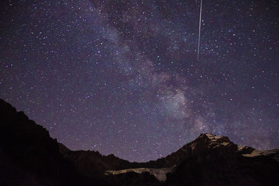 Low angle view of silhouette mountain against sky at night