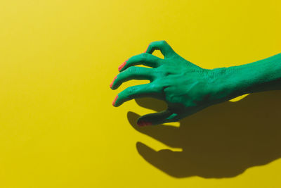 Close-up of human hand against yellow background