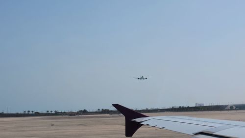 Airplane flying over runway against clear blue sky