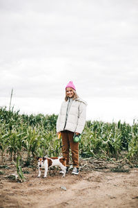 Cheerful teenage girl playing in the field with her dog jack russell terrier on the background 